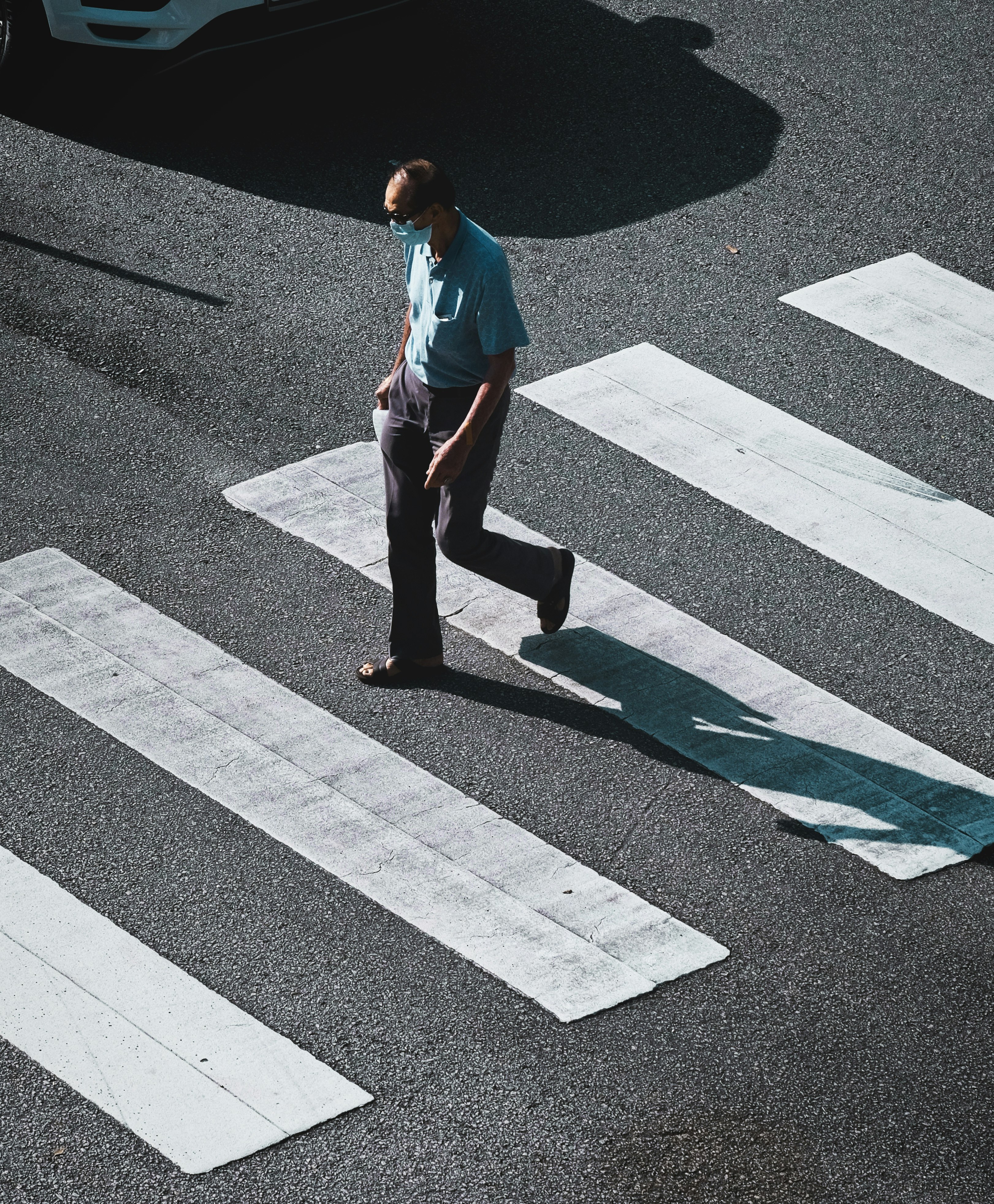 man in blue polo shirt and black pants walking on pedestrian lane during daytime